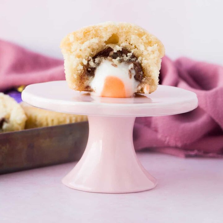 A cadbury creme egg duffin on a small pink stand.