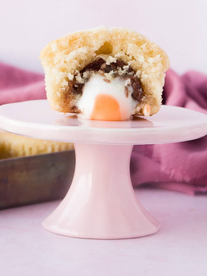 A cadbury creme egg duffin on a small pink stand.