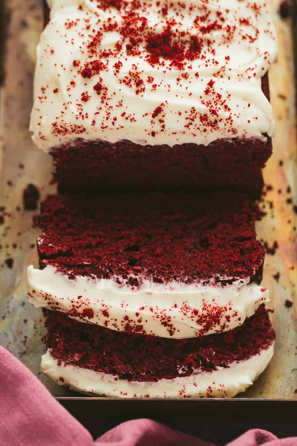 A red velvet loaf cake that has had two slices cut away. 