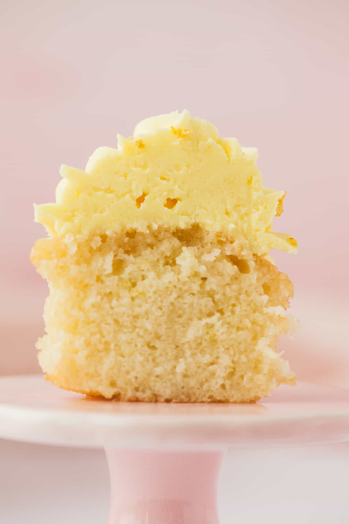 A lemon drizzle cupcake that has been sliced open to reveal it's soft moist centre. 
