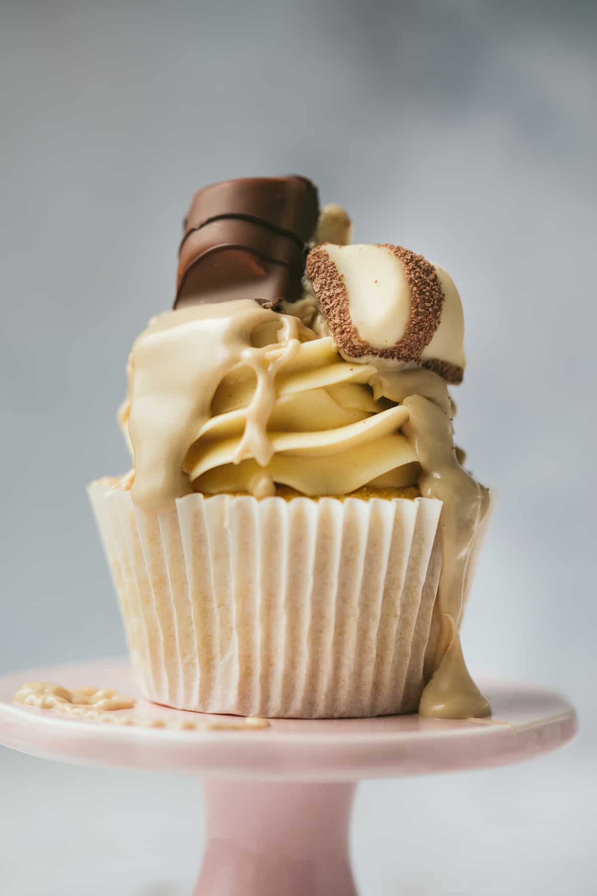 A Kinder Bueno Cupcake that has been drizzled with Kinder spread and topped with chocolate and white Kinder Bueno pieces. 