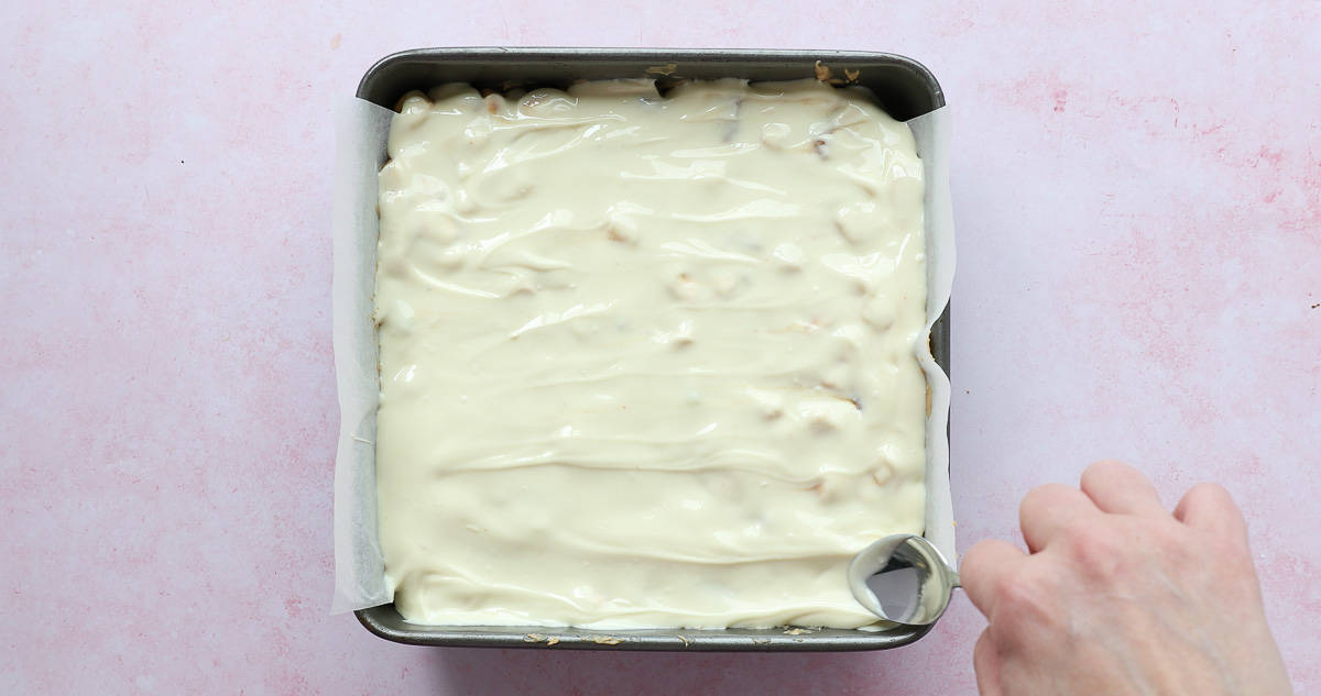 White chocolate being added to the top of a no bake fridge cake. 