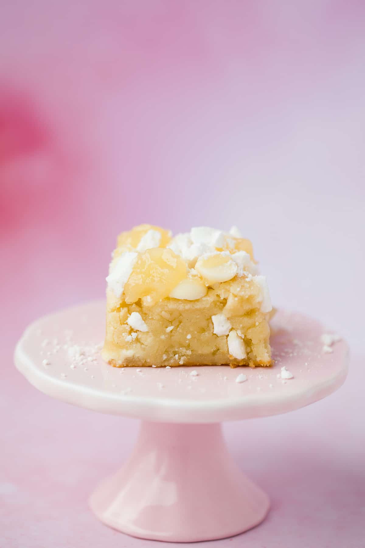 A lemon flavour blondie on a small pink cake stand. 