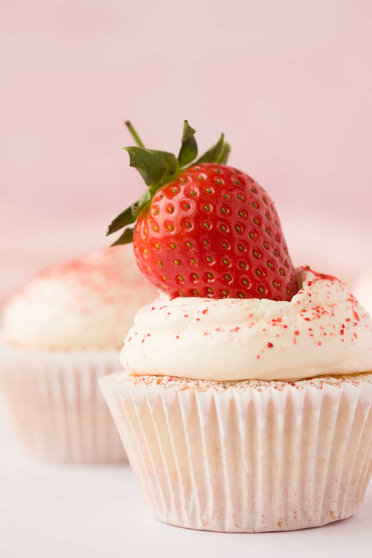 A vanilla flavoured Victoria Sponge Cupcake with icing sugar and a strawberry. 
