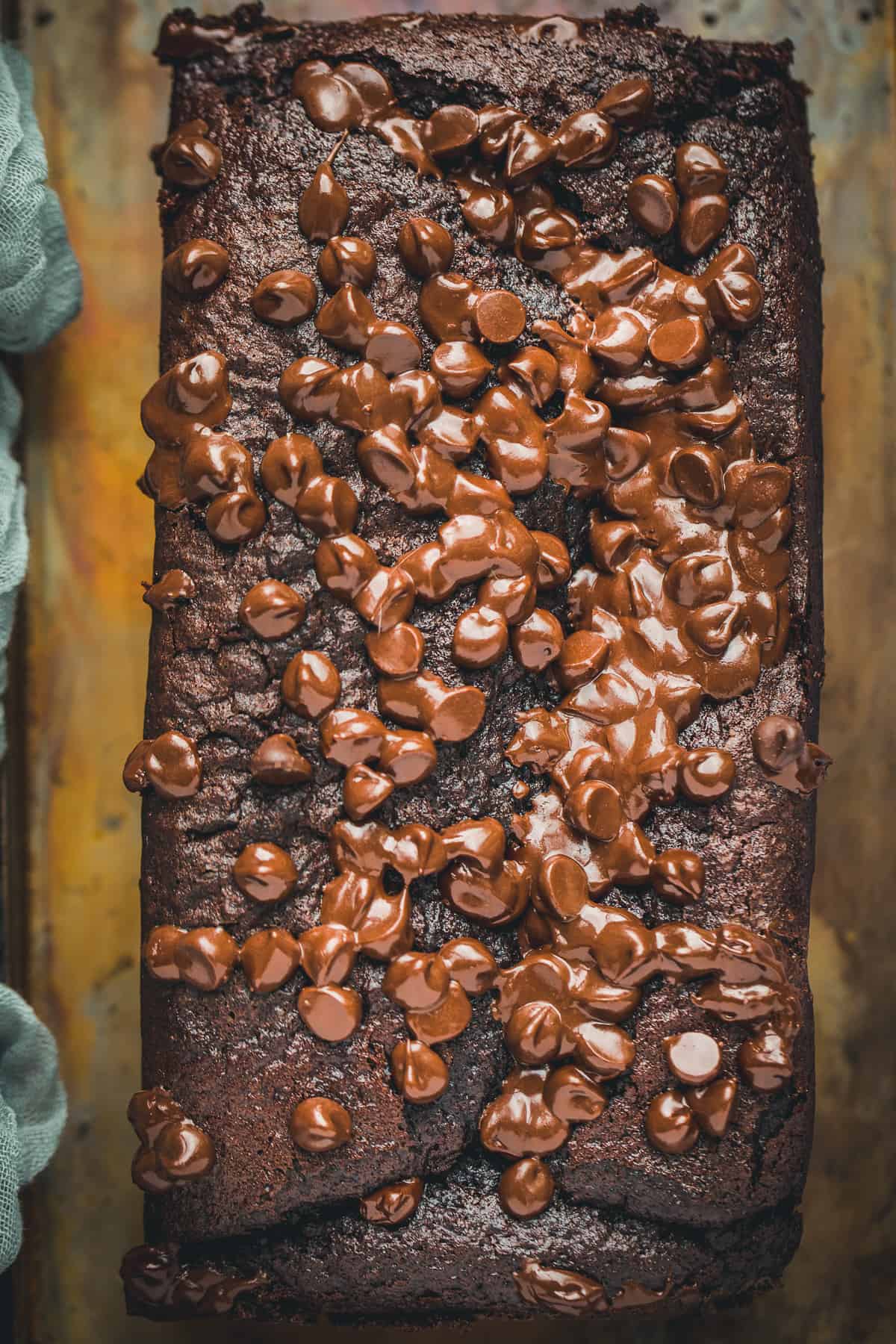 A close up image of dark chocolate chips melting on top of a cake fresh from the oven. 