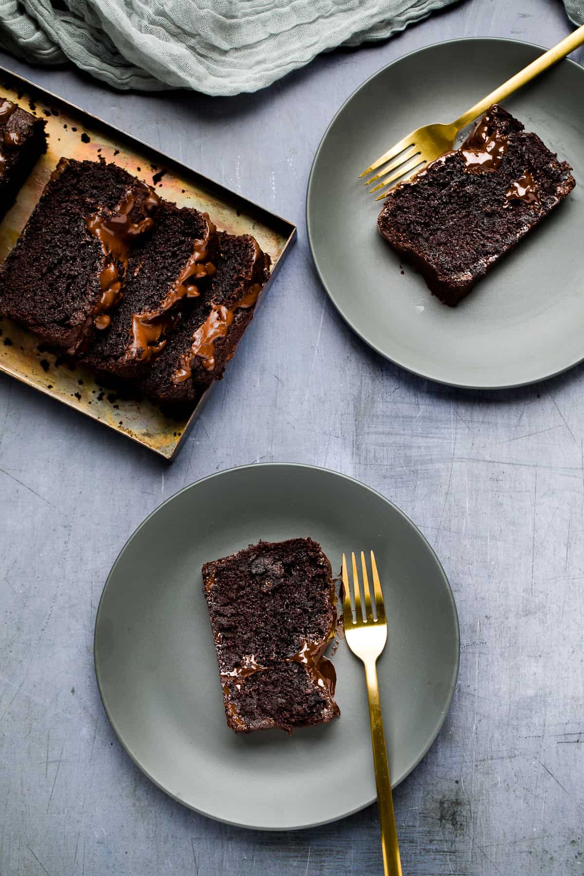 Pieces of chocolate cake on small grey plates. 