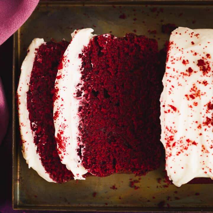 A moist red velvet cake, bright red in colour with a white coloured frosting.