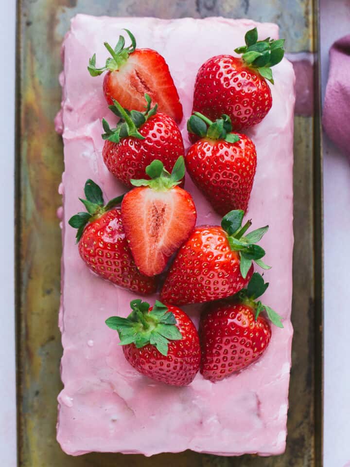 A strawberry loaf cake with a pink coloured glaze.