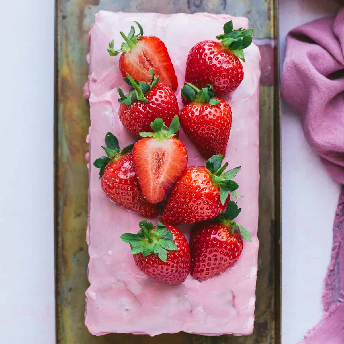 A strawberry loaf cake with a pink coloured glaze.
