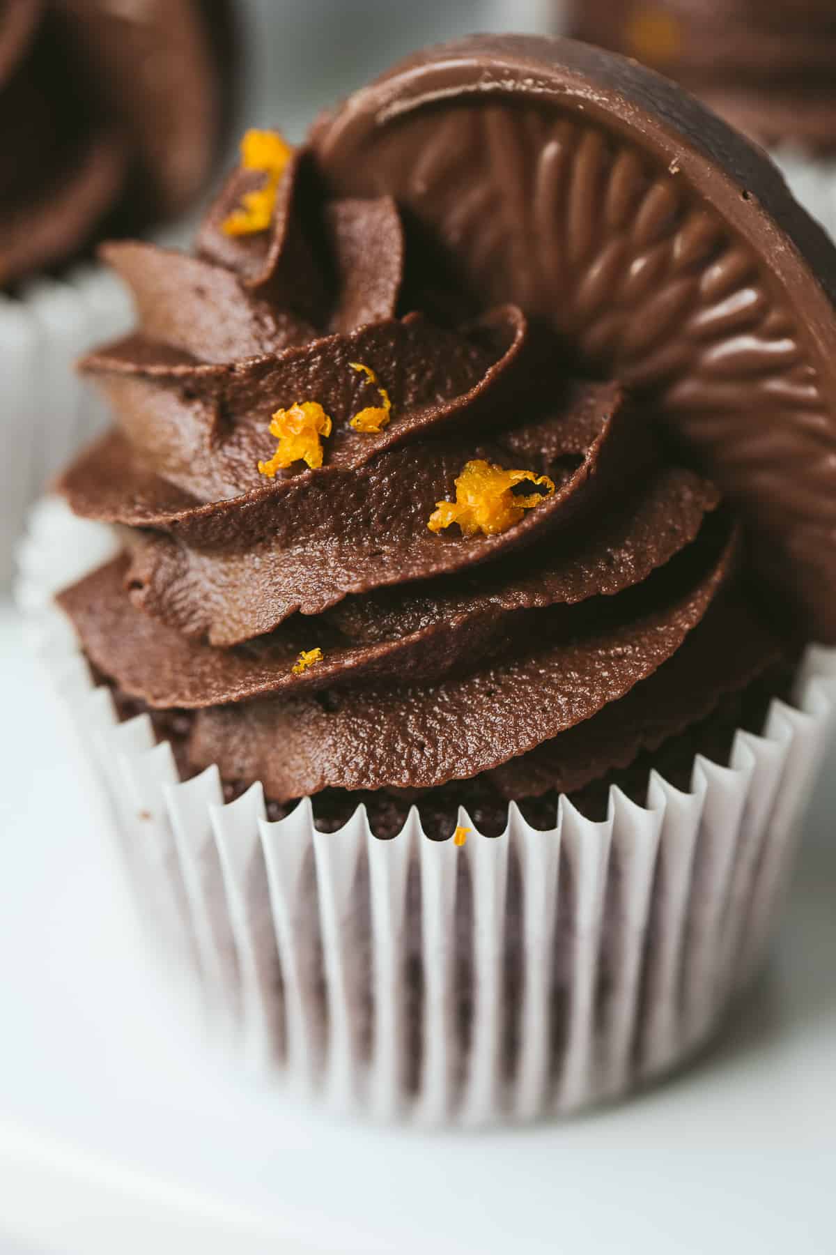 A Chocolate cupcake with chocolate buttercream in a white cupcake case. 