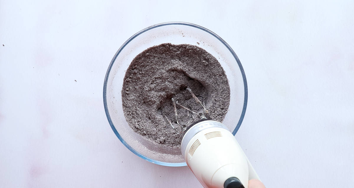 A mixing bowl containing plain flour, cocoa powder and caster sugar. 