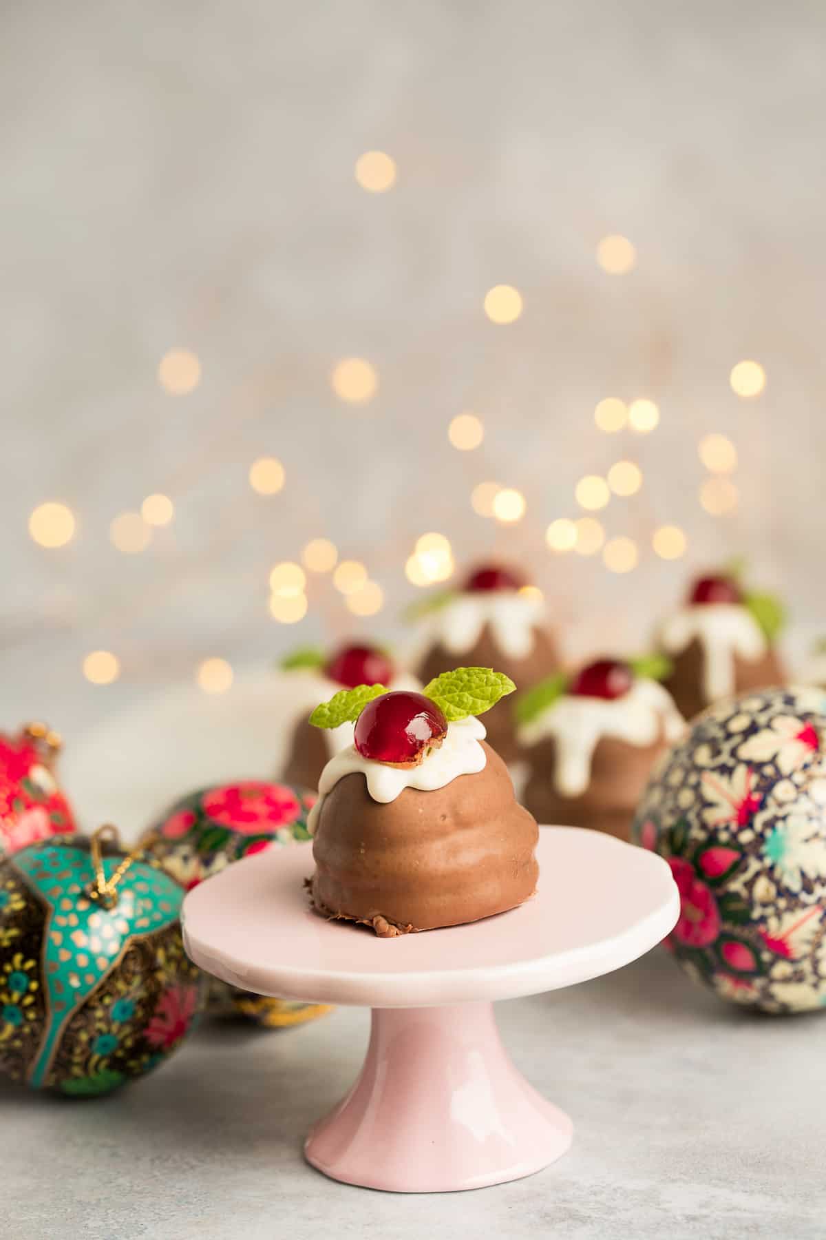A Marshmallow Chocolate covered christmas pudding on a small pink stand. 