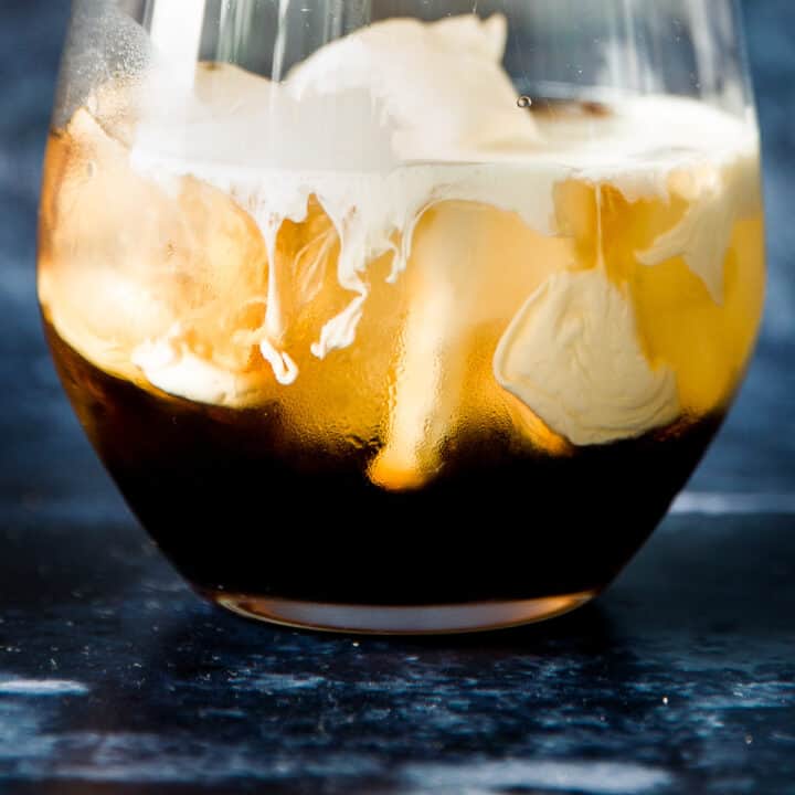 Cream being poured into a white russian cocktail.